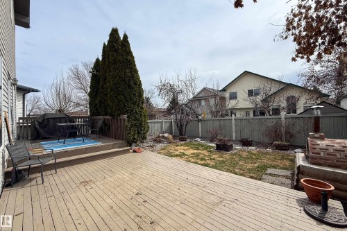 Expansive outdoor decking featuring a two-tiered design, wood railing, and a privacy screen of mature evergreens - 1205 Ormsby Lane, Edmonton, AB - Outdoor With Deck Patio Veranda