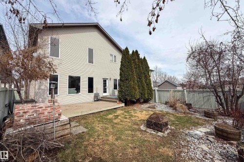 Rear exterior featuring a concrete patio, light-colored horizontal siding, and a white entry door - 1205 Ormsby Lane, Edmonton, AB - Outdoor