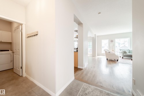 Bright interior offering a laundry area with white cabinetry, a light-toned flooring transition, and an open concept living space - 1205 Ormsby Lane, Edmonton, AB - Indoor Photo Showing Laundry Room
