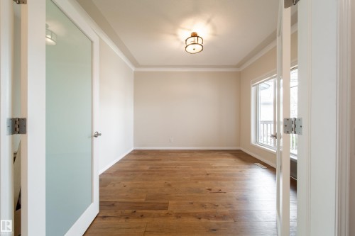 Room featuring wood-finish flooring, neutral wall tones, crown molding, and a prominent window - 1205 Ormsby Lane, Edmonton, AB - Indoor Photo Showing Other Room