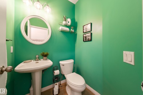 Pedestal sink with an oval mirror and a three-light vanity fixture - 1205 Ormsby Lane, Edmonton, AB - Indoor Photo Showing Bathroom