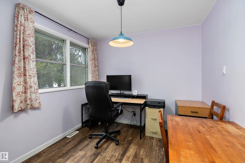 This room features wood-look flooring, light-colored walls, and a window providing natural light - 7720 85 Avenue, Edmonton, AB - Indoor Photo Showing Office