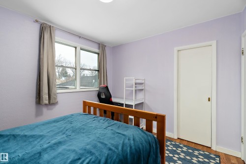 This room features light purple walls and a window with a view of trees - 7720 85 Avenue, Edmonton, AB - Indoor Photo Showing Bedroom