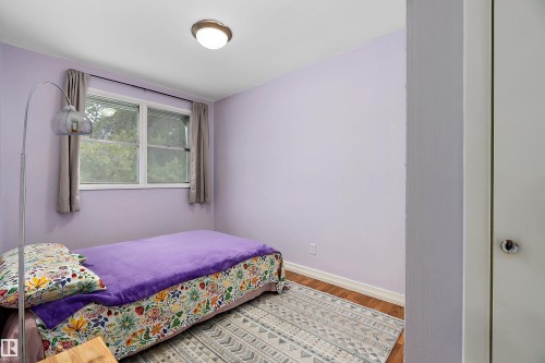 This room features a window with curtains, hardwood flooring, and a ceiling-mounted light fixture - 7720 85 Avenue, Edmonton, AB - Indoor Photo Showing Bedroom