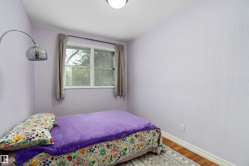 This room features a window with a view of greenery, hardwood floors, and a ceiling light fixture - 7720 85 Avenue, Edmonton, AB - Indoor Photo Showing Bedroom