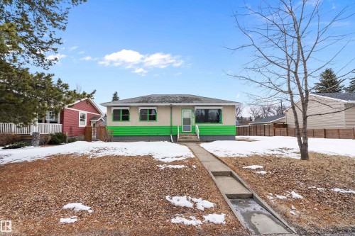 The property features a concrete pathway leading to the front entry, a light-colored exterior with a green accent, and multiple windows - 7720 85 Avenue, Edmonton, AB - Outdoor