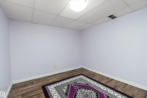 Room with light purple walls, wood-look flooring, and a drop ceiling - 7720 85 Avenue, Edmonton, AB - Indoor Photo Showing Other Room