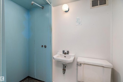 The property features a complete bathroom with a shower area, a wall-mounted sink, and a toilet - 7720 85 Avenue, Edmonton, AB - Indoor Photo Showing Bathroom