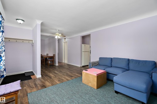 The property features wood-style flooring and light-colored walls throughout the main living areas - 7720 85 Avenue, Edmonton, AB - Indoor Photo Showing Living Room