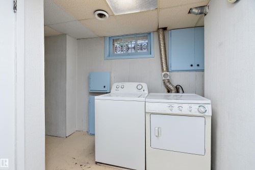 Dedicated laundry area featuring a window, overhead cabinetry, and a drop ceiling - 7720 85 Avenue, Edmonton, AB - Indoor Photo Showing Laundry Room