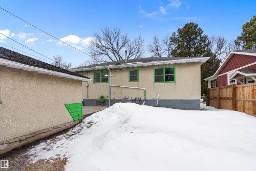 Exterior view of the property with a stucco finish, green window trim, and a black shingled roof - 7720 85 Avenue, Edmonton, AB - Outdoor
