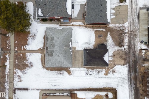 Aerial view of the property, featuring a main building with a gray shingled roof, a smaller detached structure with a dark roof, and surrounding snow-covered grounds - 7720 85 Avenue, Edmonton, AB - Outdoor