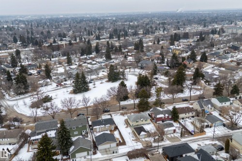 Aerial view of the neighborhood showcasing houses with various roof styles and colors, surrounded by numerous mature trees and snow-covered ground - 7720 85 Avenue, Edmonton, AB - Outdoor With View