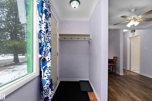 Inviting entryway featuring a window with a view of mature trees, a coat rack with a shelf, and hardwood flooring - 7720 85 Avenue, Edmonton, AB - Indoor