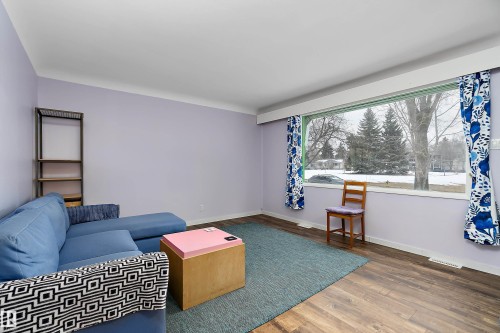 This room features wood-style flooring and a large window providing views of the outdoors - 7720 85 Avenue, Edmonton, AB - Indoor