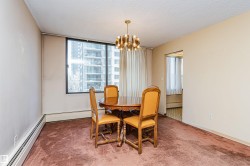 Dining area featuring a large window, textured ceiling, brown carpeting, and a built-in baseboard heater - 