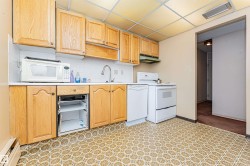 Kitchen featuring wood cabinetry, white appliances, patterned flooring, and a drop ceiling with recessed lighting - 