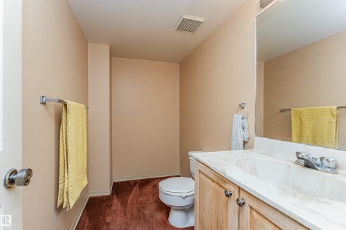 Bathroom featuring a vanity with wood-finish cabinetry, an integrated white sink, and a large wall-mounted mirror - 407 10045 118 Street, Edmonton, AB - Indoor Photo Showing Bathroom