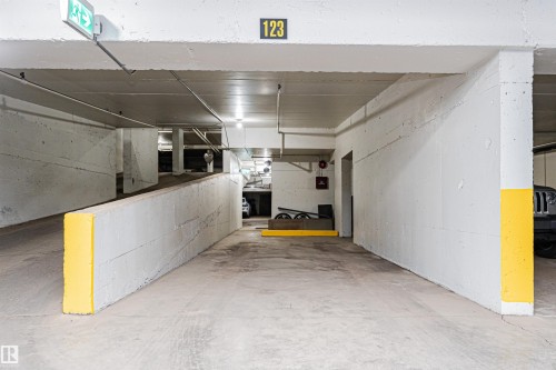 Underground parking space featuring concrete walls, concrete flooring, overhead lighting, and painted yellow safety markers - 407 10045 118 Street, Edmonton, AB - Indoor Photo Showing Other Room