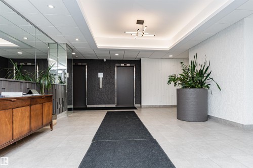 Well-lit communal hallway featuring dual elevators, recessed ceiling lights, a contemporary light fixture, and light-toned floor tiles - 407 10045 118 Street, Edmonton, AB - Indoor Photo Showing Other Room