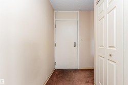 Entryway featuring a solid core door with transom window, textured ceiling, and paneled bifold closet doors - 