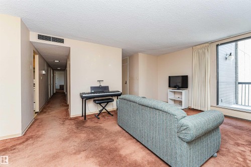 Living area with textured ceiling, wall-mounted air vent, and light-colored walls - 407 10045 118 Street, Edmonton, AB - Indoor Photo Showing Living Room