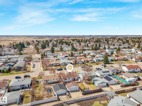Aerial perspective showcasing a residential neighborhood with detached homes, mature trees, and a clear sky - 1027 77 Street, Edmonton, AB - Outdoor With View