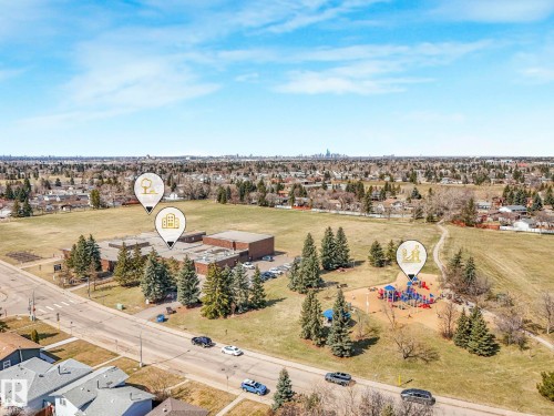 Aerial view of a suburban neighborhood featuring a school building, a large open field, and a playground - 1027 77 Street, Edmonton, AB - Outdoor With View