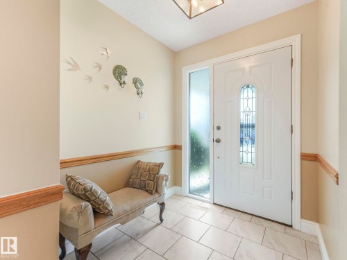 Entryway featuring a white door with decorative glass, a frosted sidelight, and light-toned tile flooring - 1027 77 Street, Edmonton, AB - Indoor Photo Showing Other Room