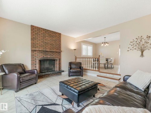 Living area featuring a brick fireplace surround with hearth, tile flooring, and light-toned wall finishes - 1027 77 Street, Edmonton, AB - Indoor Photo Showing Living Room With Fireplace