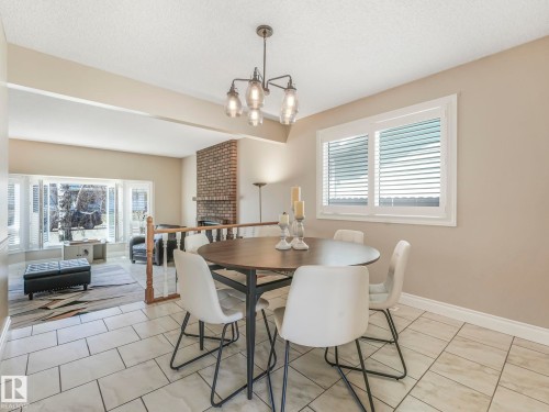 Dining area featuring a contemporary chandelier, white wall trim, and a window with white louvered shutters - 1027 77 Street, Edmonton, AB - Indoor Photo Showing Dining Room