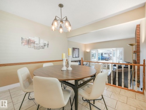 Dining area with tiled flooring, wood-finish railing, and an overhead chandelier - 1027 77 Street, Edmonton, AB - Indoor Photo Showing Dining Room