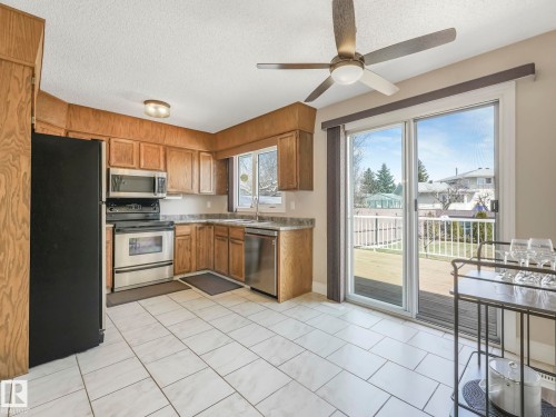 Kitchen with wood-finish cabinetry, stainless steel appliances, and a black refrigerator - 1027 77 Street, Edmonton, AB - Indoor Photo Showing Kitchen