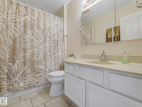 Bathroom featuring a single vanity with white cabinetry, an integrated sink, and an expansive mirror - 1027 77 Street, Edmonton, AB - Indoor Photo Showing Bathroom