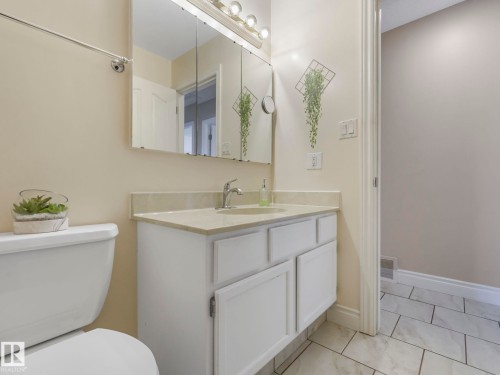 Bathroom featuring a single vanity with a light-colored countertop, a white cabinet, and a chrome faucet - 1027 77 Street, Edmonton, AB - Indoor Photo Showing Bathroom