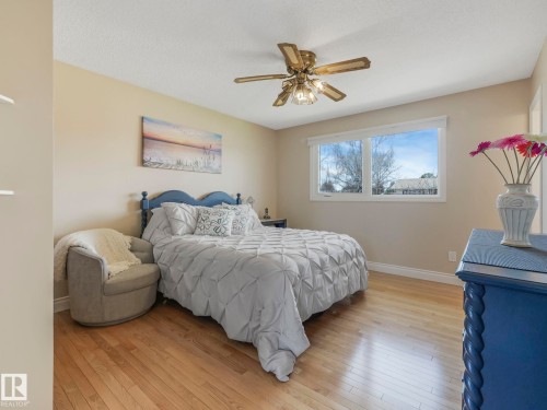 Bedroom featuring wood-finish flooring, a ceiling fan with integrated lighting, and multiple windows - 1027 77 Street, Edmonton, AB - Indoor Photo Showing Bedroom