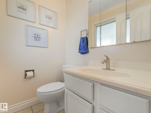 Bathroom featuring a white vanity with integrated sink, chrome faucet, and mirrored medicine cabinet - 1027 77 Street, Edmonton, AB - Indoor Photo Showing Bathroom