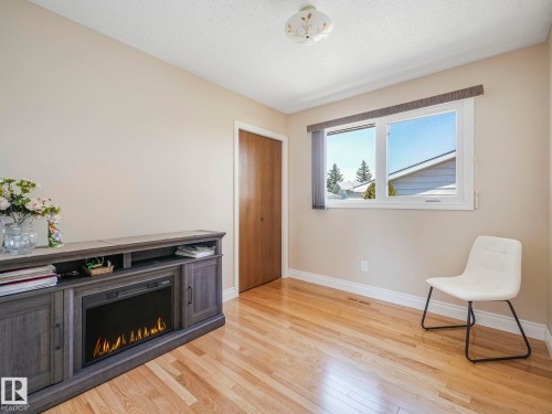 Light wood-finish flooring with white baseboards throughout - 1027 77 Street, Edmonton, AB - Indoor With Fireplace