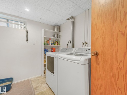 Dedicated laundry area featuring a washer and dryer pair, built-in shelving, durable flooring, a drop ceiling, and recessed lighting - 1027 77 Street, Edmonton, AB - Indoor Photo Showing Laundry Room