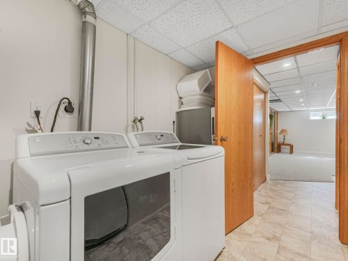 Dedicated laundry area featuring a washer and dryer, tile-look flooring, and a drop ceiling - 1027 77 Street, Edmonton, AB - Indoor Photo Showing Laundry Room