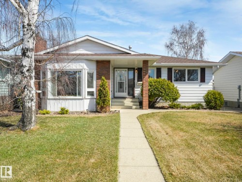 Ranch-style residence featuring white siding, a prominent bay window, brick accents, dark window shutters, and a concrete front walkway - 1027 77 Street, Edmonton, AB - Outdoor With Facade