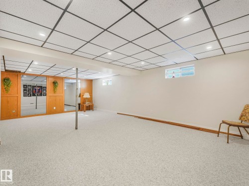 Spacious finished lower level featuring light-toned carpet flooring, a drop ceiling with recessed lighting, and light-painted walls - 1027 77 Street, Edmonton, AB - Indoor