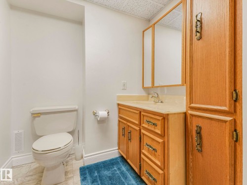 Wood-finish vanity with an integrated sink and light-toned countertop - 1027 77 Street, Edmonton, AB - Indoor Photo Showing Bathroom