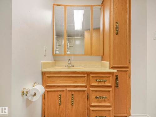 Bathroom vanity with wood-finish cabinetry, integrated sink, and light-toned countertop - 1027 77 Street, Edmonton, AB - Indoor Photo Showing Bathroom
