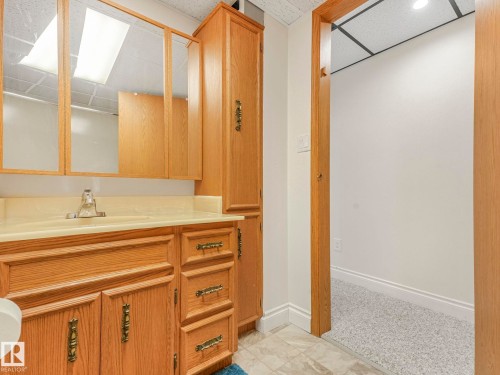 Bathroom vanity featuring a light wood finish, integrated sink, and an overhead mirrored cabinet - 1027 77 Street, Edmonton, AB - Indoor Photo Showing Bathroom