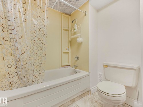 Bathroom featuring a bathtub with shower, integrated shelving, and a toilet - 1027 77 Street, Edmonton, AB - Indoor Photo Showing Bathroom