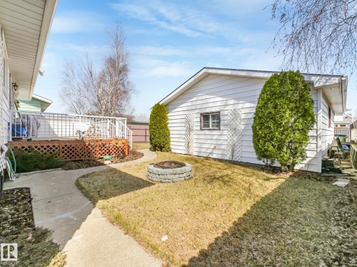 Wood deck with white railing, concrete patio, and round stone fire pit - 1027 77 Street, Edmonton, AB - Outdoor