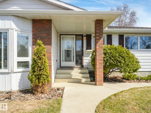 Inviting front entry featuring a covered porch, brick support columns, multi-pane glass door, and a bay window - 1027 77 Street, Edmonton, AB - Outdoor