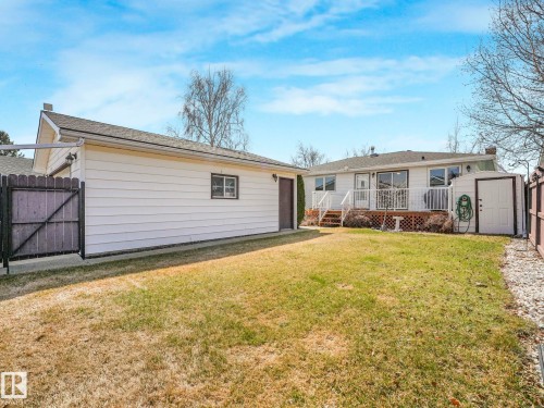 Expansive backyard featuring a detached garage, a white picket fence, a raised deck, and a storage shed - 1027 77 Street, Edmonton, AB - Outdoor