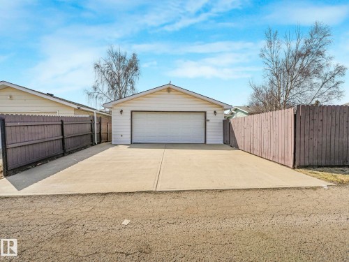 Detached garage featuring a white overhead door, exterior lighting, and a gabled roofline - 1027 77 Street, Edmonton, AB - Outdoor